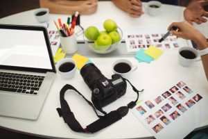Camera on desk,laptop,green apple,coffee,discussion,pen,picture,a group of discussion in office.