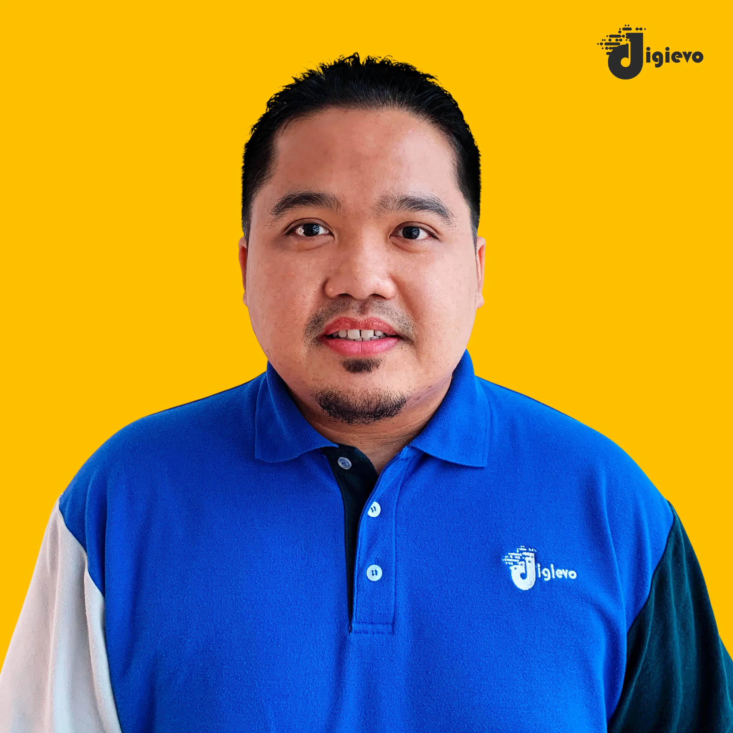 Lelaki berwajah serius memakai baju polo biru dalam foto potret berlatar kuning.