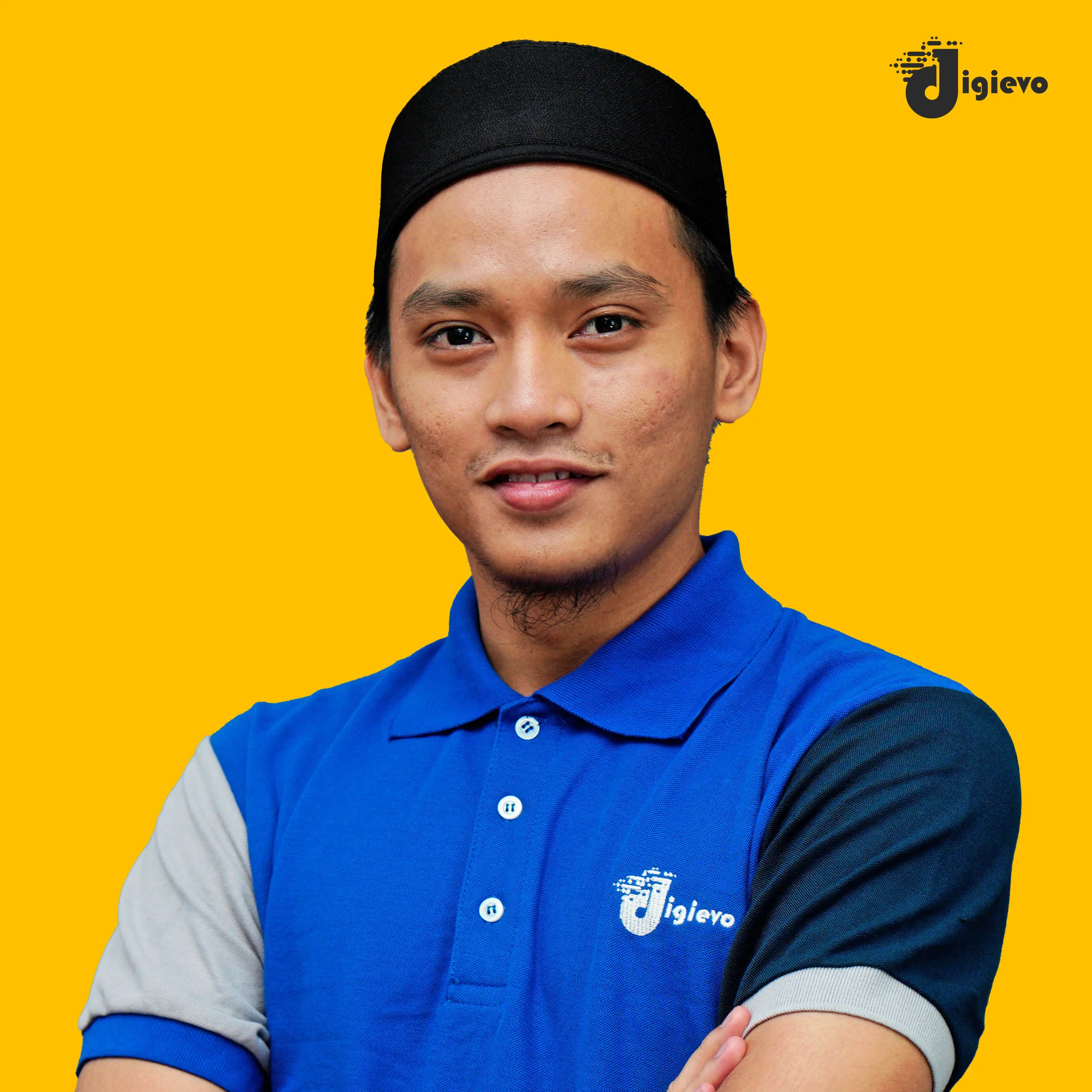 Lelaki bertopi songkok hitam memakai baju polo biru berlatar belakang kuning.