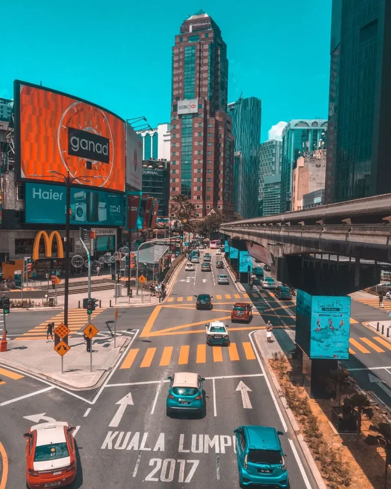 Busy street view of Bukit Bintang, Kuala Lumpur, with tall buildings, billboards, and moving traffic.