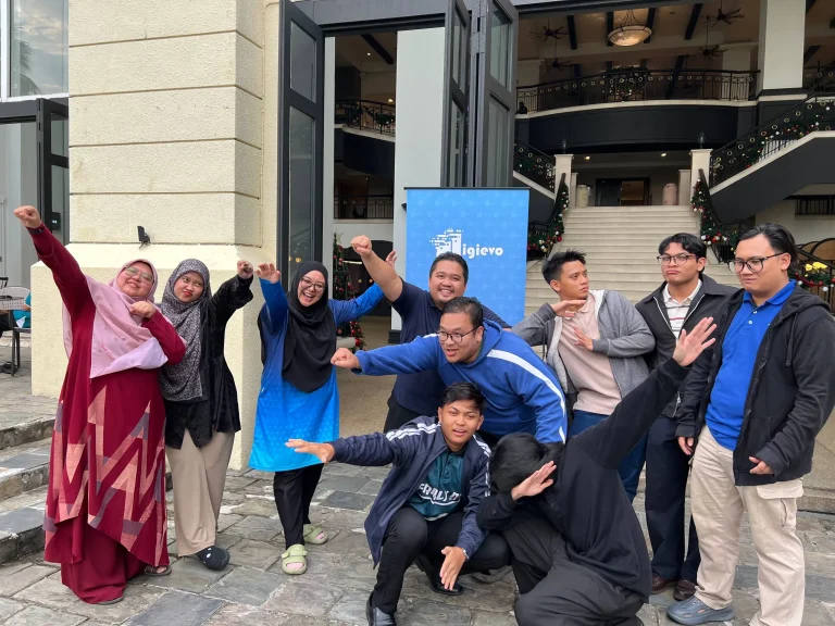 Pasukan Digievo bergambar bersama dengan pose kreatif semasa acara syarikat di luar bangunan